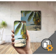 Une personne tient un smartphone à la main qui affiche un motif de plage. Une image similaire avec des rayures verticales est accrochée au mur.