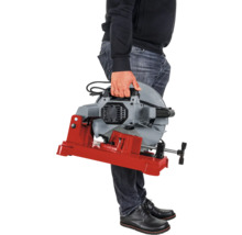 Une personne tient une scie à métaux avec une base rouge.