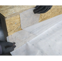 Pose d'une bâche de construction sur une structure en bois pour la protection.