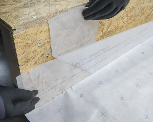 Pose d'une bâche de construction sur une structure en bois pour la protection.