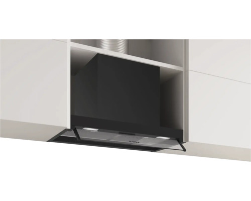 Dunstabzugshaube in einer Küchenzeile mit weißen Schränken und einem silbernen Rohr.