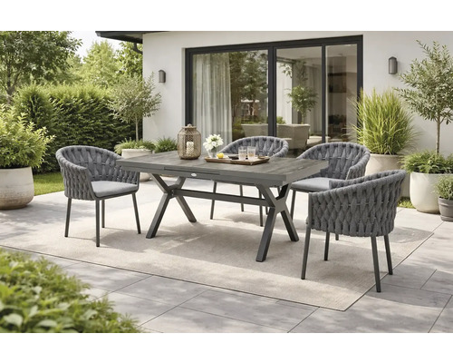 Scène de jardin avec table à manger en bois et quatre chaises avec détails tressés.