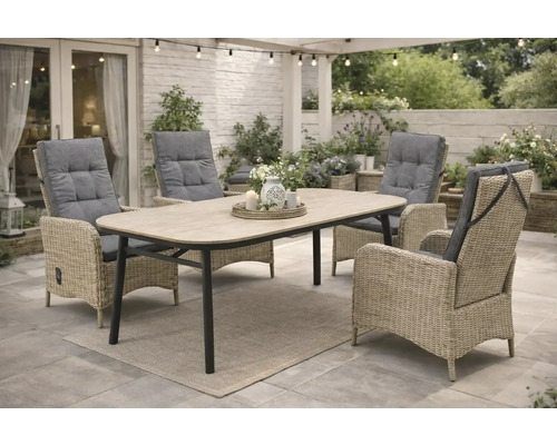 Gartensitzgruppe mit Esstisch und vier Korbsesseln mit Polsterauflagen auf einer Terrasse.