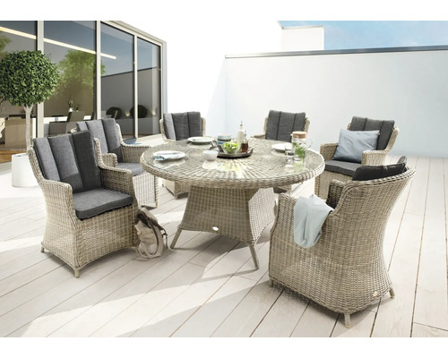 Scène de jardin avec table à manger ronde et six chaises en rotin avec coussins gris