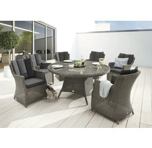 Gartenszene mit einem runden Esstisch aus Rattan und sechs passenden Sesseln mit Polsterauflagen auf einer Terrasse.