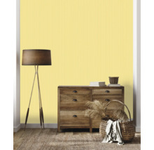 Séjour avec commode, lampadaire, paniers et papier peint rayé jaune.