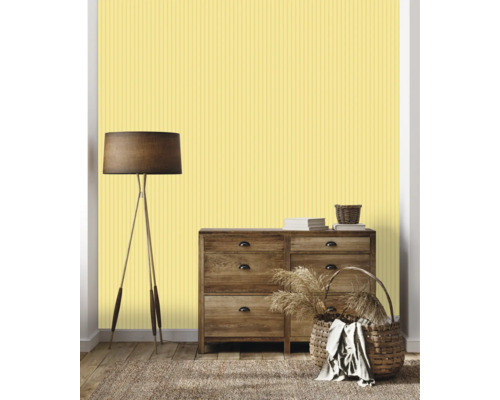 Séjour avec commode, lampadaire, paniers et papier peint rayé jaune.