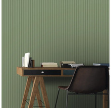 Scène avec bureau, livres, machine à écrire et chaise devant un mur à rayures.