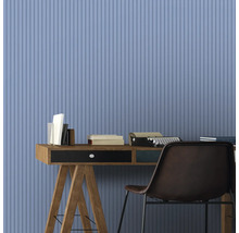 Bureau avec bureau, livres, machine à écrire et chaise devant un mur avec un motif à rayures verticales