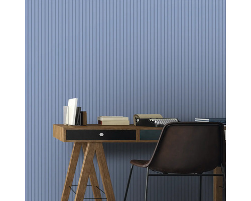 Bureau avec bureau, livres, machine à écrire et chaise devant un mur avec un motif à rayures verticales
