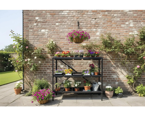 Étagère à fleurs à trois niveaux devant un mur de briques avec des rosiers et des compositions florales.