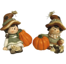 Deux figurines décoratives au design automnal avec des citrouilles.