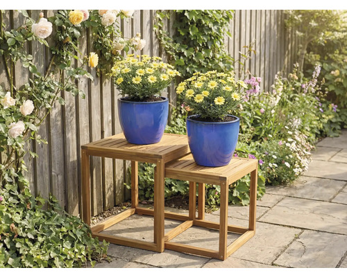 Deux pots de fleurs bleus avec des marguerites jaunes sur deux tables d'appoint en bois dans le jardin.