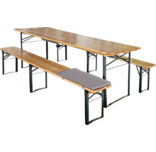 Ensemble de brasserie en bois avec table, deux bancs et un coussin gris, piètements pliables en métal.