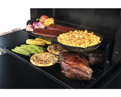 Aliments préparés sur un gril, notamment des côtes levées, des macaronis au fromage, du rôti de porc, des pizzas, des asperges, du maïs et des poivrons.