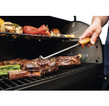 Barbecue avec de la viande et des légumes retournés avec une pince à barbecue