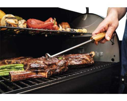 Barbecue avec de la viande et des légumes retournés avec une pince à barbecue