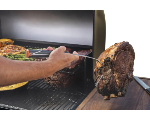 Un homme vérifie la température à cœur d'un morceau de viande sur un gril avec un thermomètre de grill