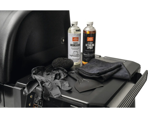 Kit de nettoyage pour barbecue Traeger avec dégraissant, spray d'entretien, grattoir, éponge, chiffon et gants sur une tablette de barbecue.