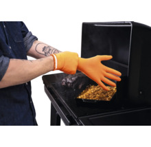 Gant de barbecue résistant à la chaleur en silicone utilisé sur un barbecue avec de la viande et un plat à four.