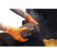 Mains avec gants en nitrile orange tenant un morceau de viande au-dessus d'un barbecue.