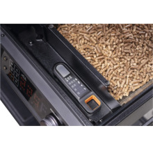 Thermomètre à viande numérique sur un barbecue à granulés avec des granulés de bois dans le réservoir.