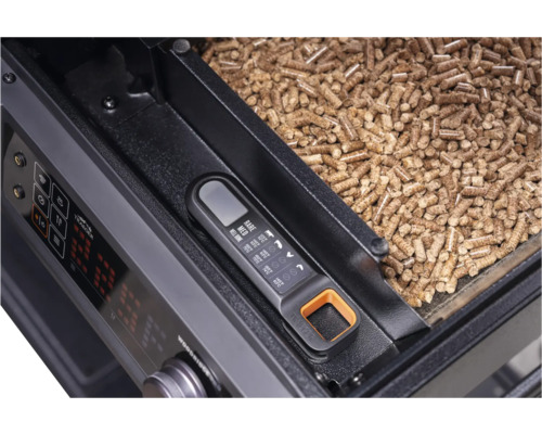 Thermomètre à viande numérique sur un barbecue à granulés avec des granulés de bois dans le réservoir.