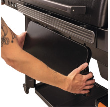 Klappbare Seitenablage eines schwarzen Grills wird per Hand nach unten geklappt.
