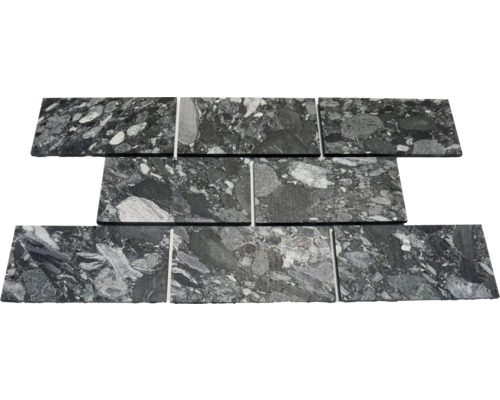 Carreaux en pierre naturelle en pose décalée, granit noir et gris avec veinage marqué et inclusions claires.