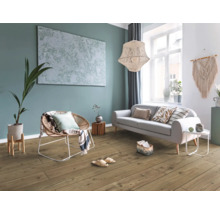 Modernes Wohnzimmer mit Bodenbelag in Holzoptik, Sofa, Rattan-Sessel und großformatigem Wandbild an einer Akzentwand.