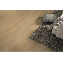 Laminatboden in Eichenoptik verlegt in einem hellen Wohnzimmer mit grauem Hochflor-Teppich und Sofa.