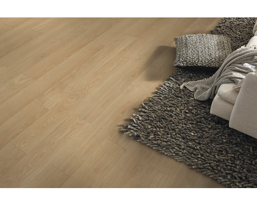 Laminatboden in Eichenoptik verlegt in einem hellen Wohnzimmer mit grauem Hochflor-Teppich und Sofa.