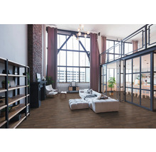 Geräumiges Loft-Wohnzimmer im Industriestil mit Boden in Holzoptik, großer Fensterfront, Backsteinwand und modernen Möbeln.