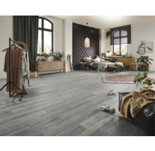Grauer Bodenbelag in Holzoptik in einem weitläufigen Schlafzimmer mit dunkler Musterwand, Bett, Kleiderständer und Zimmerpflanzen.