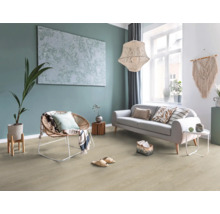 Helles Wohnzimmer mit Boden in Holzoptik, grauem Sofa, Korb-Sessel, großer Hängeleuchte und Wanddekoration im Boho-Stil.