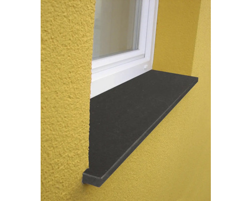 Außenfensterbank aus Naturstein in Anthrazit, montiert an einer Fassade unter einem weißen Fensterrahmen.