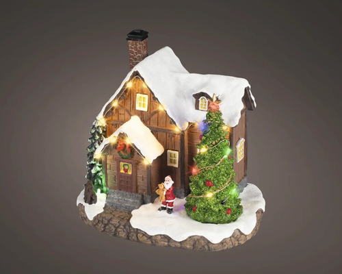 Maison miniature de Noël en bois avec toit enneigé, sapin illuminé et petite figurine de Père Noël.