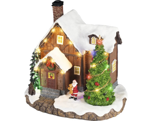 Village de Noël miniature avec une maison enneigée, un sapin illuminé, une figurine de Père Noël et une guirlande lumineuse.
