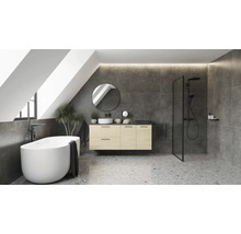 Salle de bains moderne sous les combles avec baignoire en îlot, meuble sous vasque en bois, miroir rond et douche italienne sur sol terrazzo.