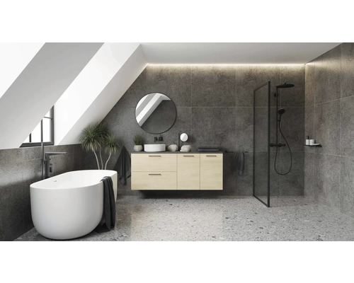 Salle de bains moderne sous les combles avec baignoire en îlot, meuble sous vasque en bois, miroir rond et douche italienne sur sol terrazzo.