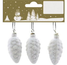 Drei weiße, glitzernde Christbaumkugeln in Form von Zapfen an einer Kartonverpackung mit weihnachtlichem Motiv.