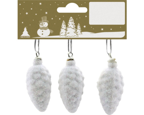 Drei weiße, glitzernde Christbaumkugeln in Form von Zapfen an einer Kartonverpackung mit weihnachtlichem Motiv.