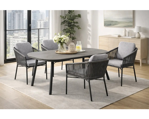 Ensemble de salle à manger moderne avec table ovale gris foncé et quatre chaises de jardin tressées avec coussins gris dans une pièce lumineuse.