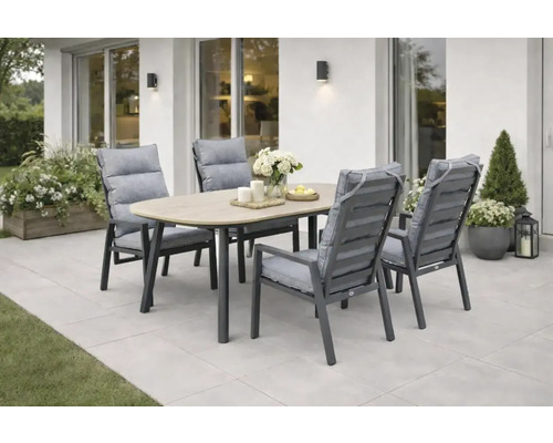 Salon de jardin composé d une table ovale aspect bois et de quatre chaises de jardin grises avec coussins sur une terrasse claire.
