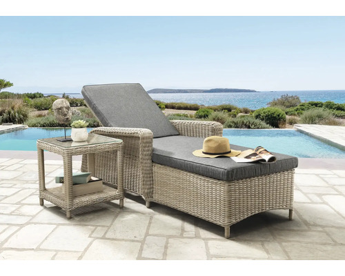 Polyrattan-Sonnenliege mit grauen Polstern und passendem Beistelltisch auf einer Terrasse am Pool mit Meerblick.