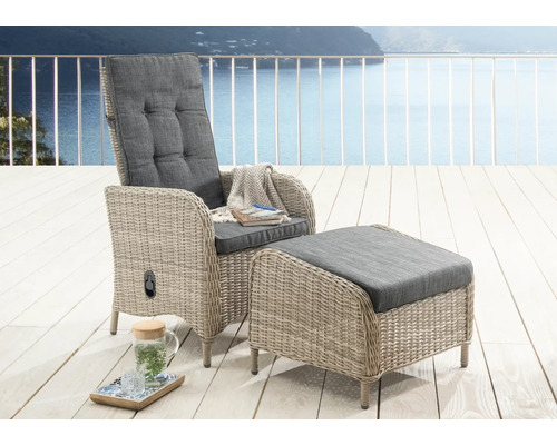 Gartensessel mit Hocker aus hellgrauem Geflecht und dunklen Polstern auf einer hellen Holzterrasse in organisierter Atmosphäre mit Wasserblick.
