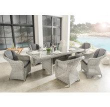 Ensemble de jardin moderne en résine tressée claire avec table en verre et six fauteuils avec coussins gris sur une terrasse organisée et lumineuse.