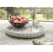Plateau tournant lumineux en résine tressée grise avec plateau en verre sur une table de jardin ronde avec bol de fruits et tasses à l'extérieur.