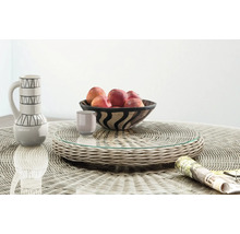 Plateau de service rotatif en résine tressée avec surface en verre sur une table de jardin assortie avec coupe à fruits et pichet.