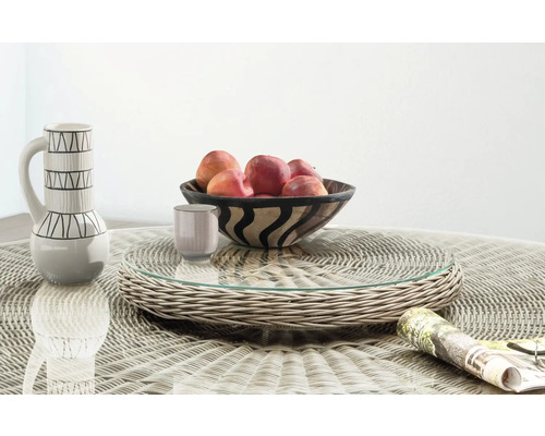 Plateau de service rotatif en résine tressée avec surface en verre sur une table de jardin assortie avec coupe à fruits et pichet.